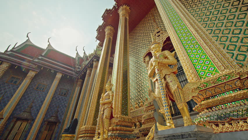 Golden guardian statues and ornate temple facade at Wat Phra Kaew in Bangkok, traditional Thai architecture in Thailand.