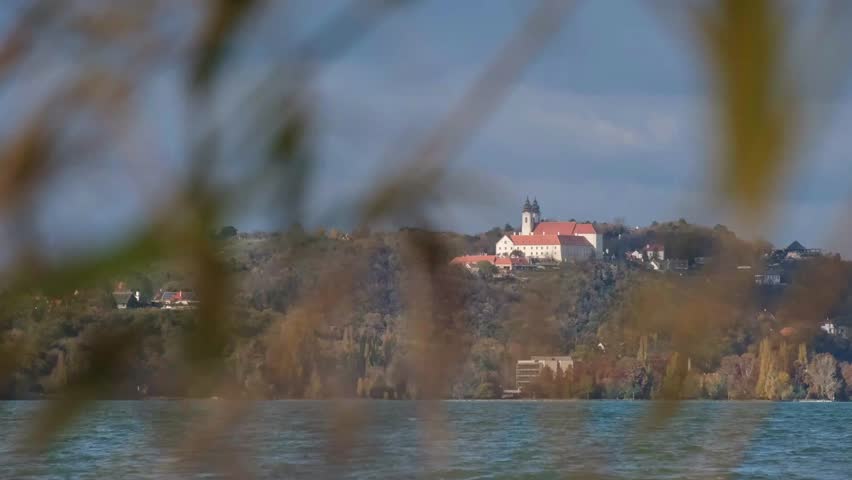 Close-up of the famous Benedictine monastery on the Tihany peninsula on a sunny autumn afternoon. Out of focus reeds and wavy water of Lake Balaton in the foreground. Slow motion landscape in Hungary.