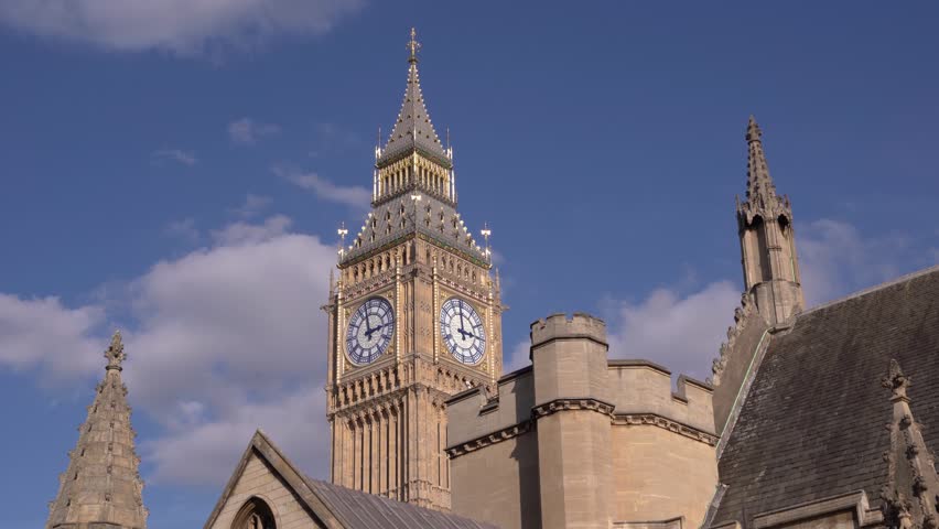 Elizabeth Tower commonly known as Big Ben and Houses of Parliament

A majestic low-angle view of the Elizabeth Tower (commonly known as Big Ben) at the Palace of Westminster in London, captured on a sunny morning. The intricate details of the clock face and the Gothic Revival architecture are set against a striking deep blue sky dotted with puffy white clouds. This iconic symbol of British democracy is a quintessential example of Victorian design and a must-see landmark for travelers visiting the UK.