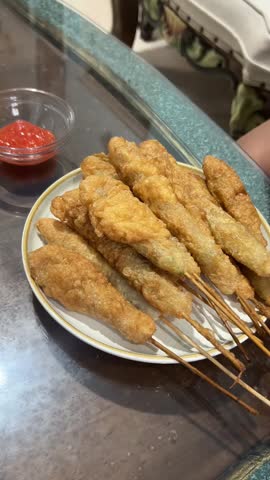 Hand Taking Fried Snack Skewer and Dipping into Sauce, Street Food Snack Picked from Plate and Dipped