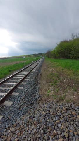 Long Perspective View of Railway Tracks Leading to Horizon Under Cloudy Sky