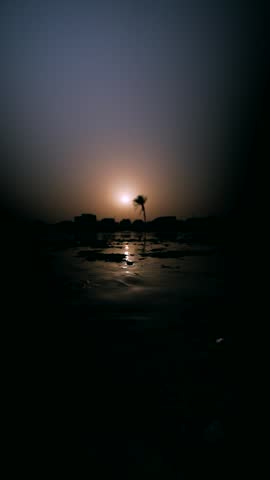Tropical beach at sunset with orange and pink sky hues.