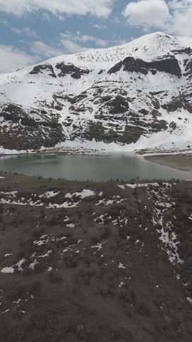 Mountain Lake Surrounded by Snow Covered Peaks and Rocky Landscape. 