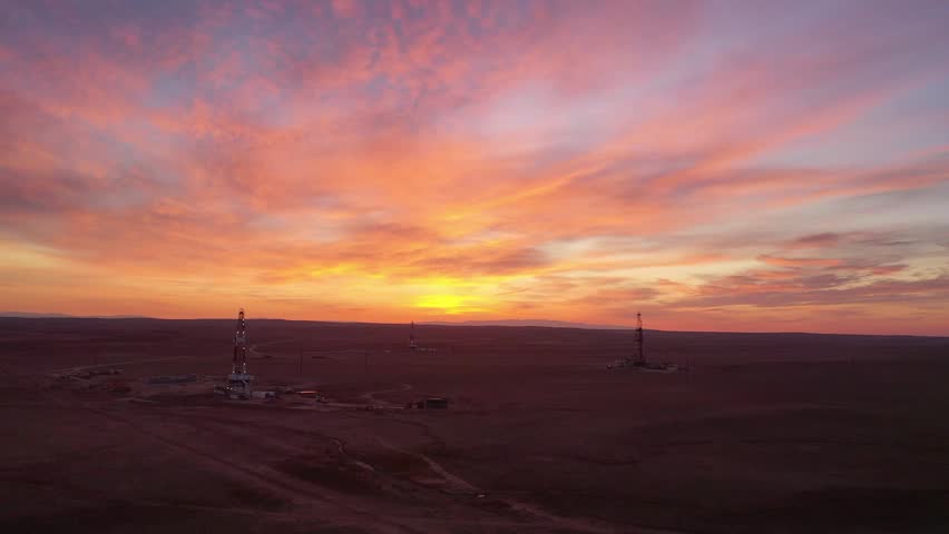 Vivid sunset over oilfield landscape with industrial atmosphere.