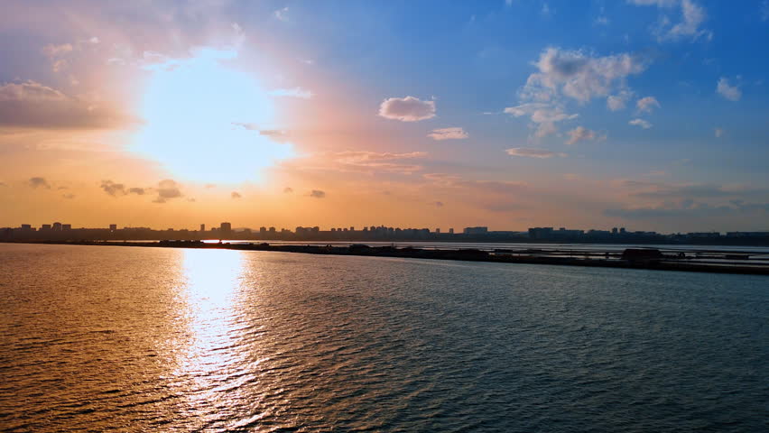 City skyline at sunset over water. Sun sets over the water as the skyline of the city spans the horizon during late evening hours.