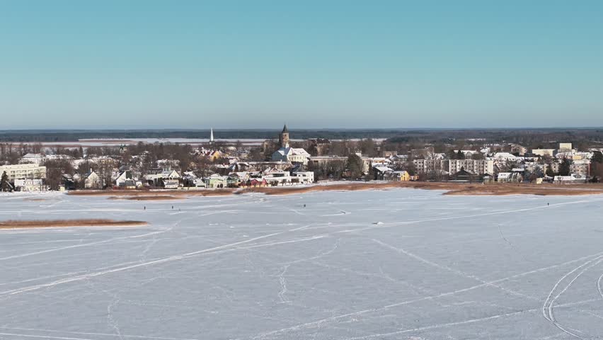 Frozen lake in foreground with Haapsalu town buildings and church in Estonia