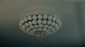 Beautiful modern fashionable ceiling chandelier sparkling with its glass elements on a white glossy ceiling. View through sparkling particles. Shot in motion - Powered by Shutterstock - Get 15% off with code: PIKWIZARD15