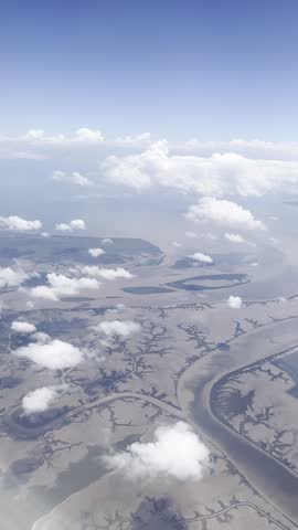 Aerial video captured through an airplane window above the Capricorn Coast, Queensland, Australia. Rivers, canals and coastal waterways wind through the flat tropical landscape far below, offering a rare and adventurous bird