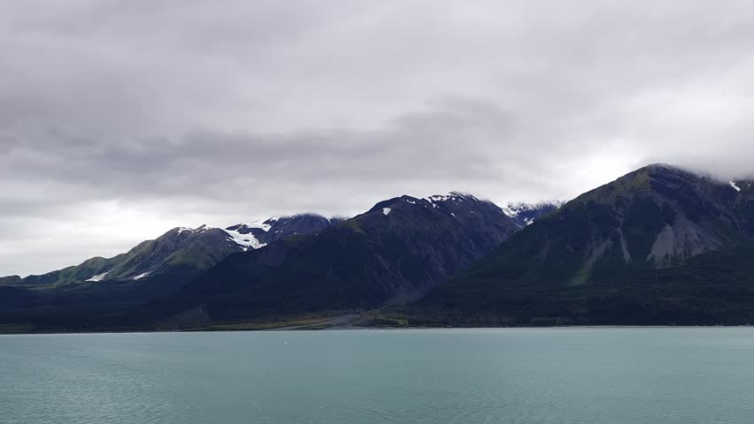Alaska, USA - View of Hubbard Glacier and the surrounding mountains. The glacier meets the water, creating a stunning landscape of ice and ocean. The mountains are covered with forests.