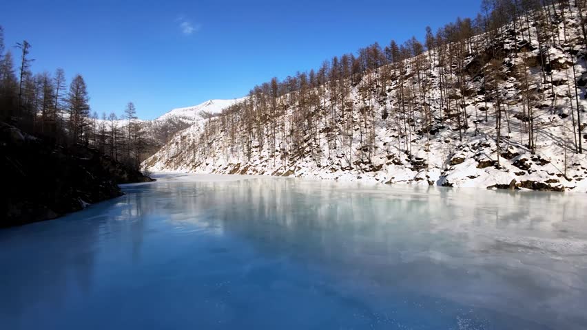 Serene winter landscape featuring a frozen lake and snow-covered mountains. A tranquil scene perfect for nature or travel projects.