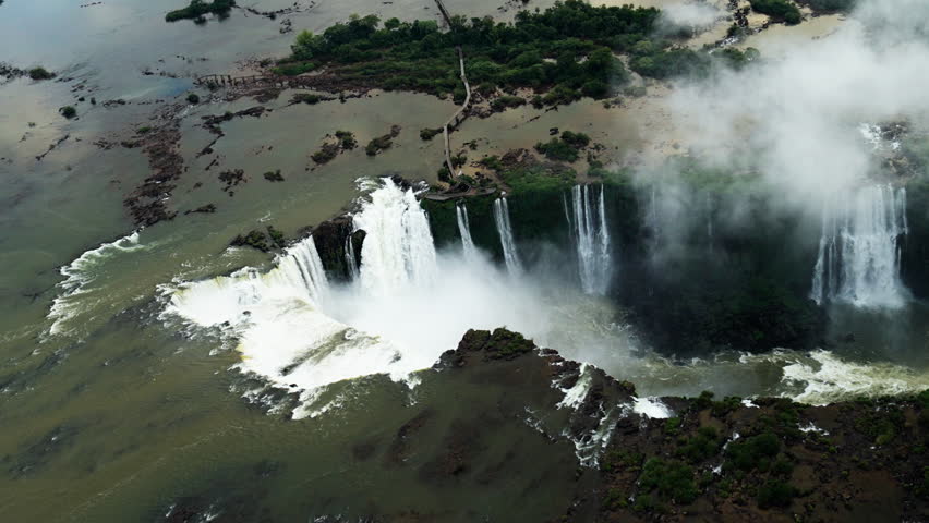 Aerial view of Iguazu Falls spanning Brazil and Argentina, showcasing massive cascading waterfalls, mist, and surrounding rainforest. Ideal for travel, nature, and documentary visuals of iconic South