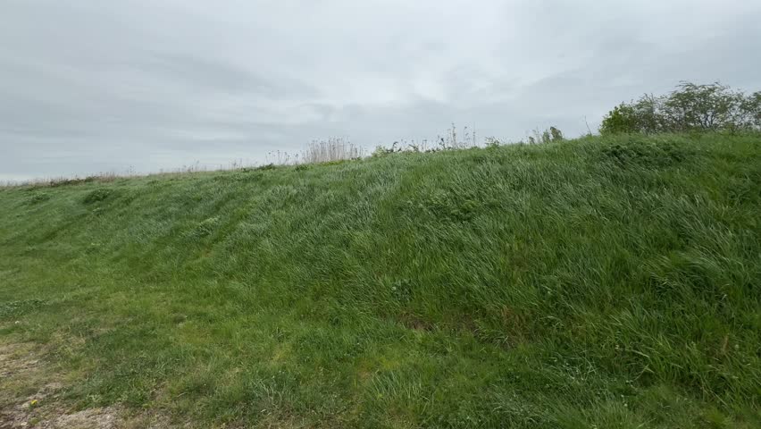 Grassy countryside hillside under cloudy sky with rural footpath
