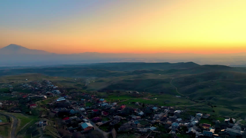 Sunset over rural hills with winding road and scattered homes