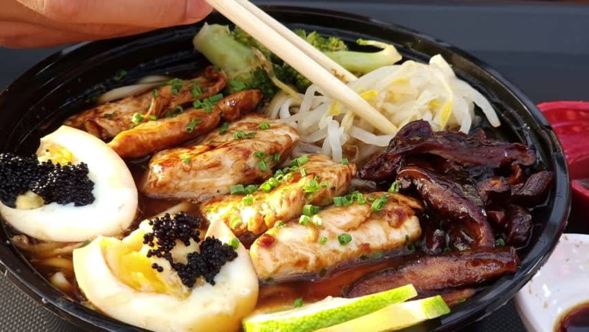 An extreme macro shot of a steaming bowl of ramen. The focus is on the rich textures of succulent grilled chicken strips garnished with green onions, soft-boiled egg halves topped with black tobiko caviar, wood ear mushrooms, and fresh bean sprouts. Wooden chopsticks are seen gently interacting with the ingredients in a dark, flavorful broth.