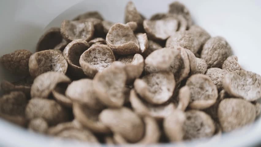 Milk Being Poured onto the Chocolate Cornflakes. pouring milk into a bowl with chocolate cereals. Chocolate flakes or chocolate crunch cereal for breakfast.