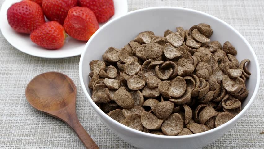 Chocolate flakes or chocolate crunch cereal for morning breakfast. milk falling in to the cocoa cereal. Milk Being Poured onto the Chocolate Cornflakes.