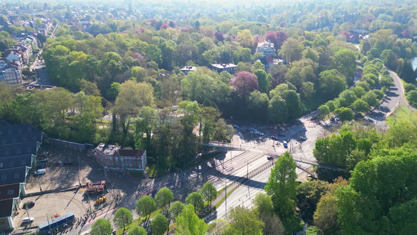 Aerial view of a lush green park with a road intersection and a pedestrian bridge in Woluwe-Saint-Pierre, Bruxelles, Belgium.