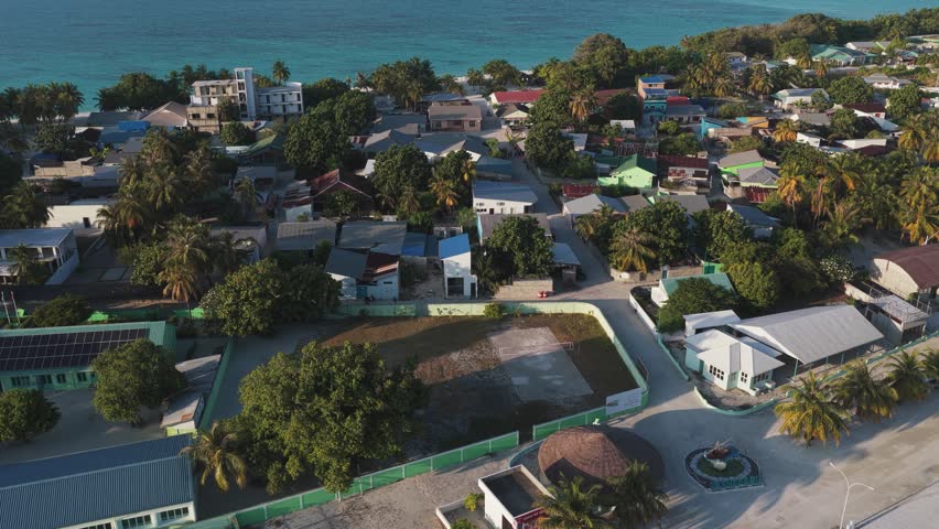 Aerial view of the coastal village of Vashafaru featuring colorful houses, lush palm trees, and the turquoise ocean in the background Vashafaru, Haa Alif Atoll, Maldives.