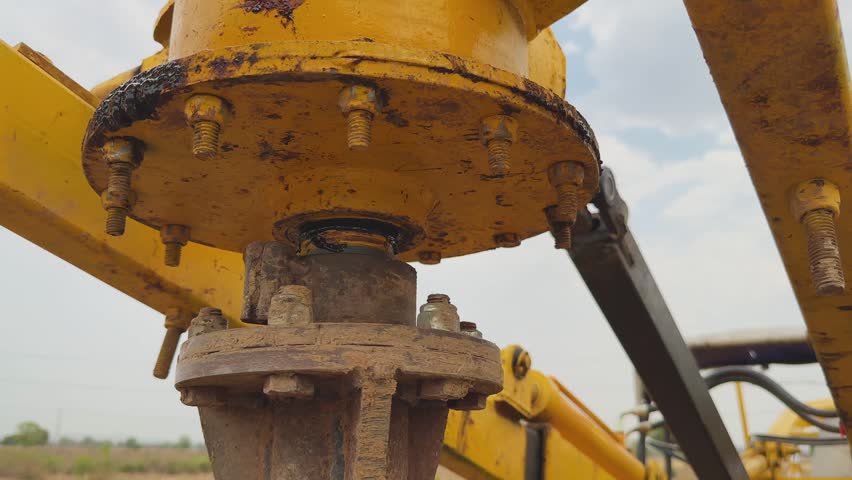 Close view of auger drive head and mounting assembly spinning as drill penetrates ground for fencing, metal bolts and mechanism visible in a rural outdoor setting