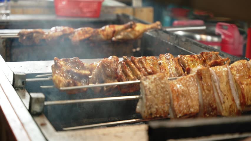 Vietnamese Street Food BBQ Grilled pork Skewers rotating on Charcoal Grill at Night Market