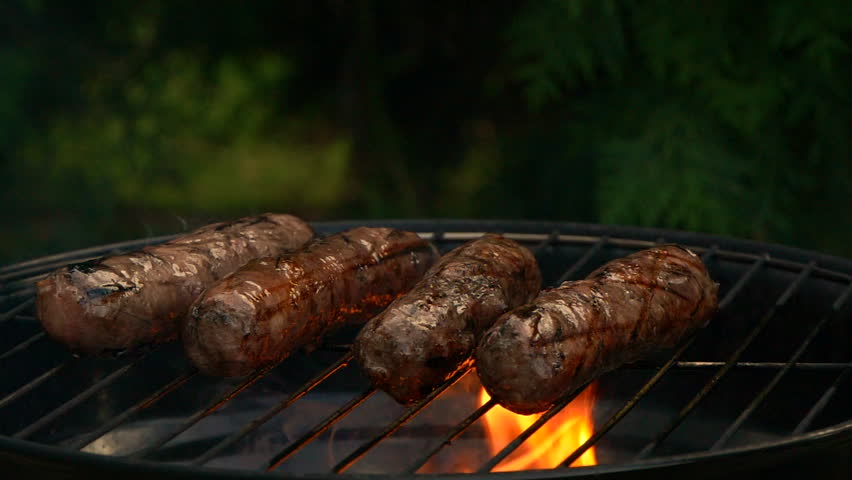 Close-up sausages on bbq grill, cooking hot dogs, slow motion grill fire flame