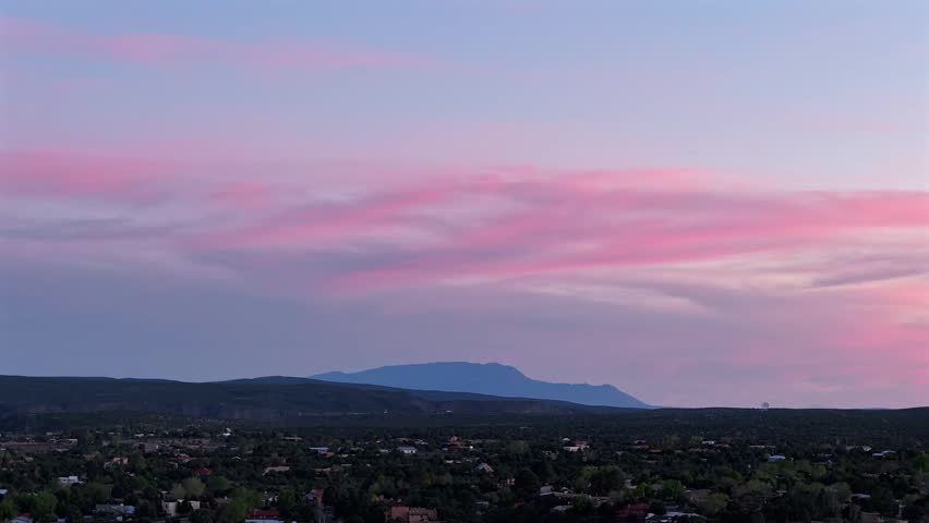 A cinematic 4k drone timelapse captures colorful sunset clouds fading over the Sandia Mountains in New Mexico. The vibrant afterglow and shifting light create an epic nature background.