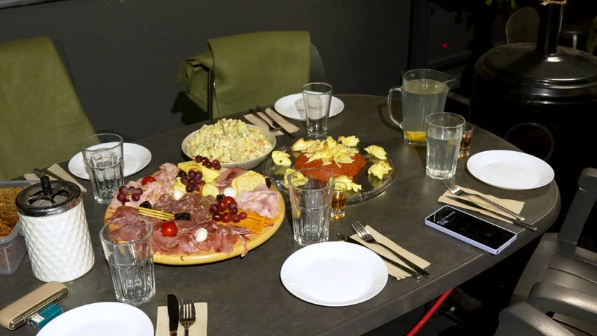 French Salad And Platter Of Cured Meats And Cheeses On Dining Tables For Christmas Dinner. high angle, panning shot