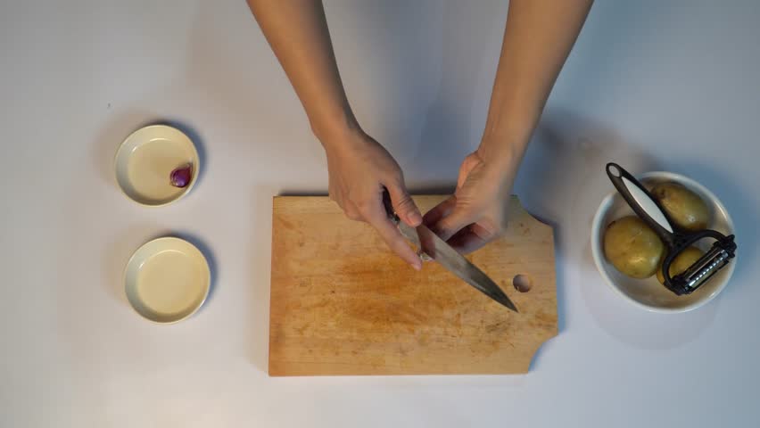 Top View of Hands Peeling Fresh Garlic on Wooden Cutting Board