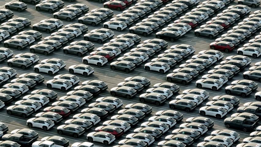 Aerial drone view of thousands of vehicles parked at a modern automotive factory, reflecting mass production, global supply chains, and the rapid growth of the modern automobile industry. 4k.
