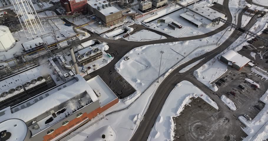 Aerial view of an industrial plant with cooling units and storage tanks covered in fresh snow in Reading, Ohio, United States.