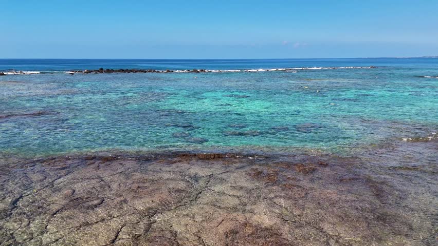 Aerial view of the crystal clear turquoise waters and volcanic rock shoreline of Kahalu
