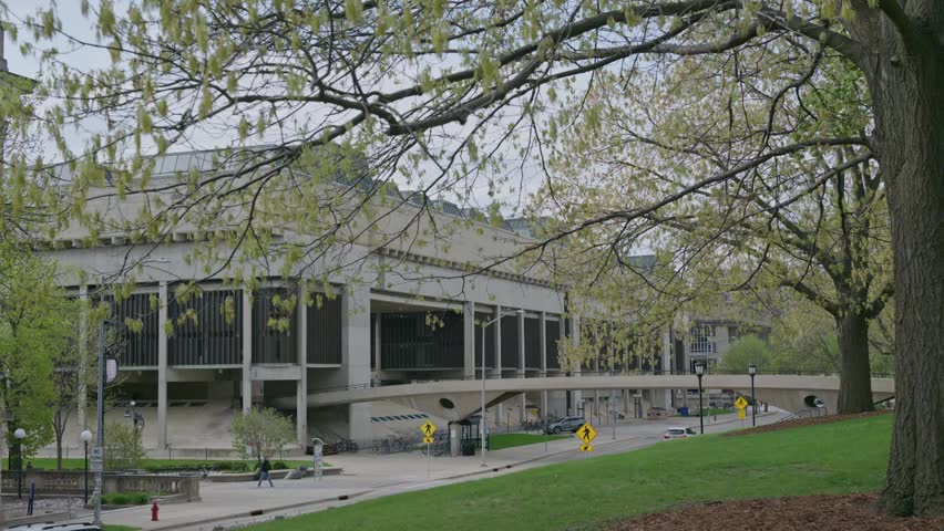 Cinematic gimbal dolly shot of University of Wisconsin campus road leading to walking bridge with smooth stabilized motion outdoors.
