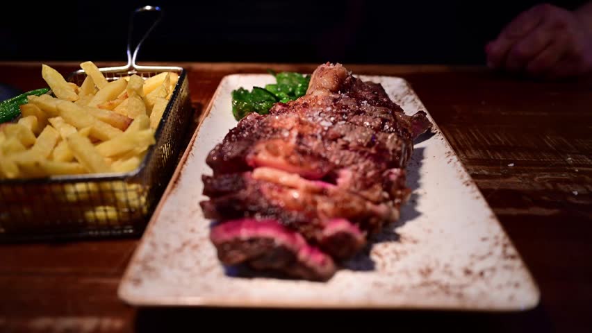 Delicious grilled t-bone steak served with french fries and padron peppers