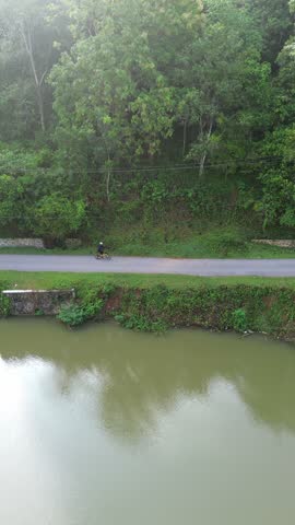 Person Riding Biycycle on Path Near Water
