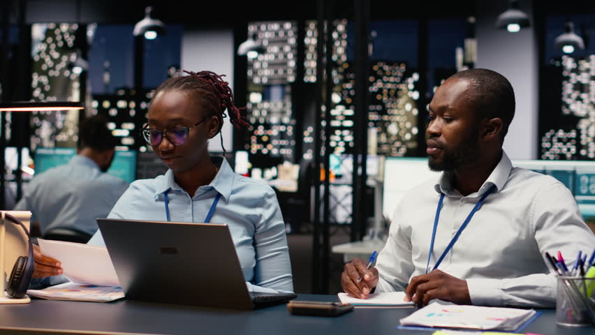 Two staff members reading emails and solving tasks together on laptop at desk, office workers analyzing data on notebook. Accounting work and interpreting statistical information.