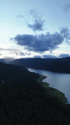 Mountain Lake at Dusk with Dramatic Storm Clouds and Forested Shore