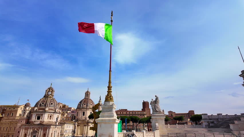 Italian national flag waving in the wind against a clear blue sky on top of the Altare della Patria in Rome
