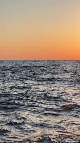 Vibrant sunset illuminated by warm orange light over a calm sea horizon