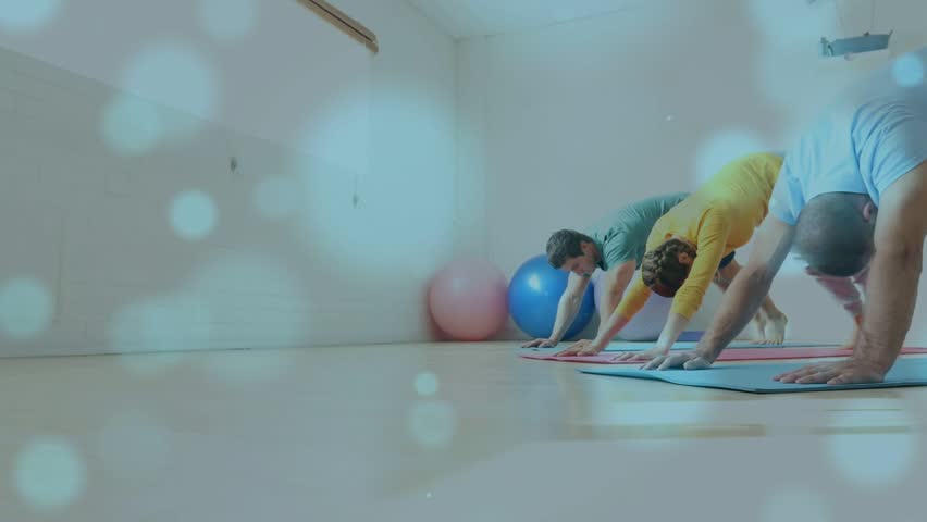 Three adults holding pose on mats, starting single-leg lifting for yoga, bokeh accenting leg lifts. Group, fitness, studio, coordinated, balance, mobility, ball