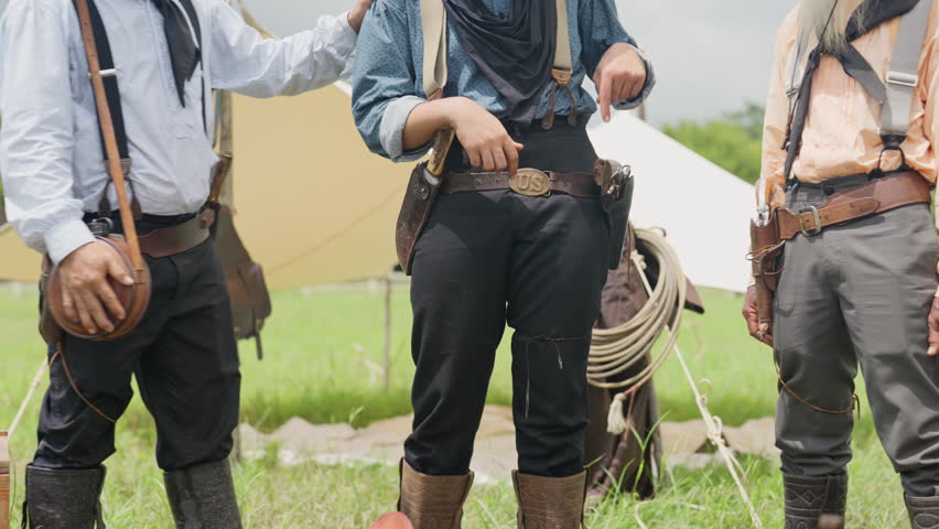 Young man shows spin or twirl a gun to the other senior and adult man in the caravan group with day light.