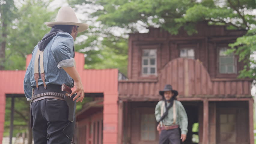 Two men were having a cowboy-style gun duel, and one of them lost and got shot in front of cowboy style building.