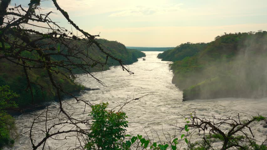 Flowing Nile River at Murchison Falls, Uganda, with water spray rising from the cascading falls.