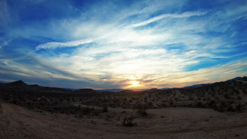 Sunset over a desert landscape with mountains and blue sky