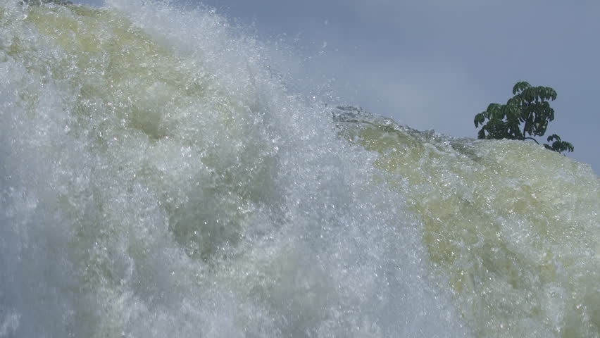 Powerful waterfall with massive water flow, mist and foam under cloudy sky
