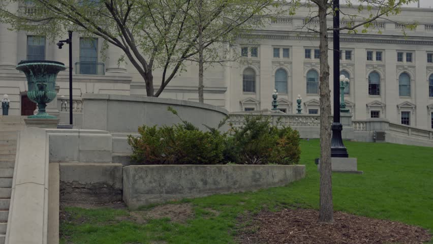Cinematic gimbal tilt up and pan left shot of Wisconsin State Capitol building exterior with smooth stabilized camera movement.