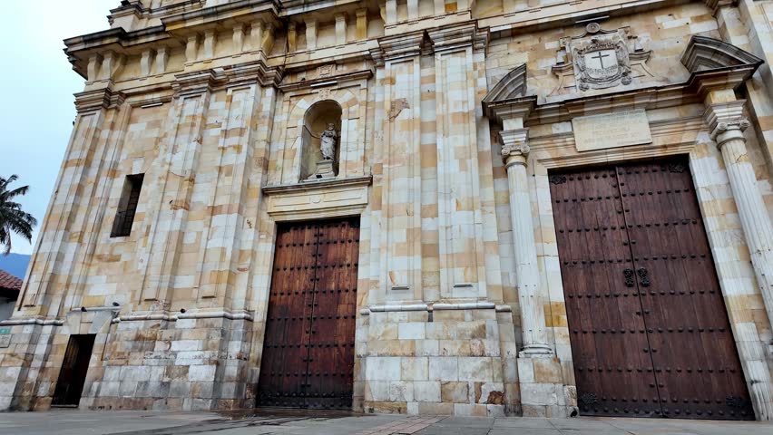 Close-up view of the intricate stonework and wooden doors of the historic neoclassical cathedral in Plaza de Bolivar.