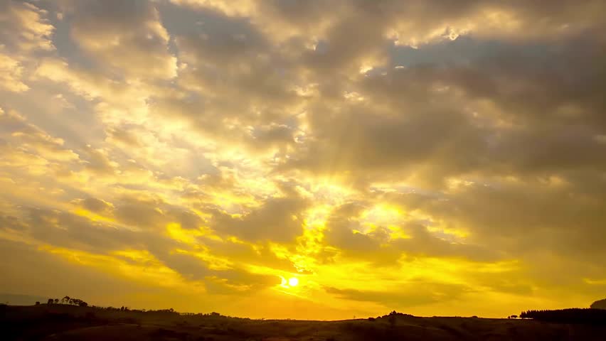 Dramatic golden sunset sky with moving clouds and sunbeams