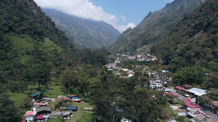 Drone aerial footage of a small mountain town surrounded by steep green valleys in the Colombian Andes.