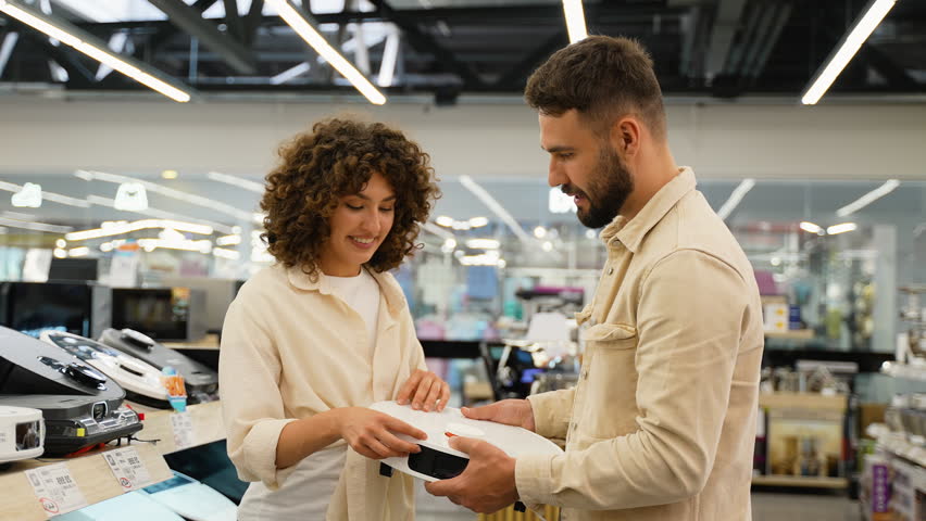 Couple examining robot vacuum cleaner in electronics store