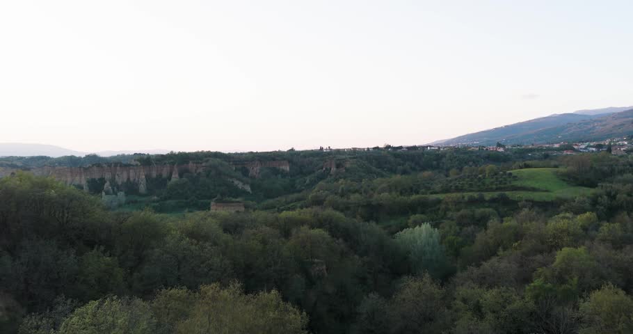 Aerial view of the Balze del Valdarno erosion formations surrounded by dense green forest and rolling hills, Castelfranco Piandisco, Tuscany, Italy.